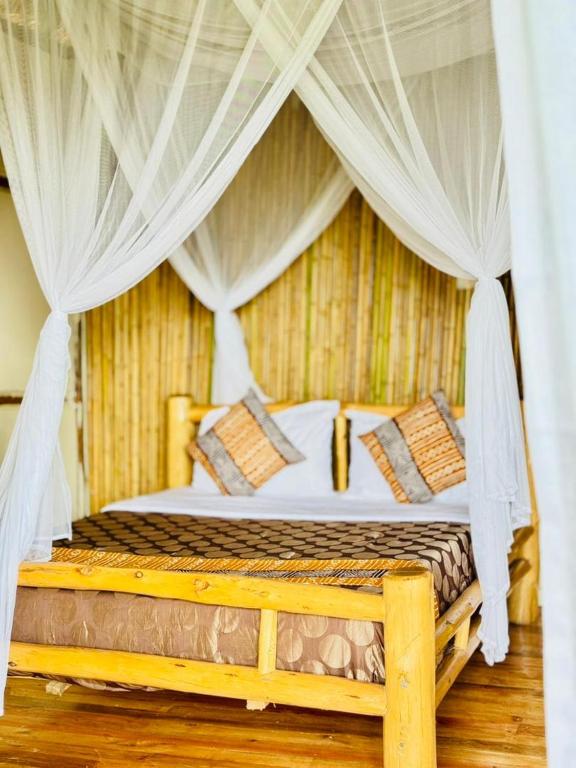 a bedroom with a bed with white drapes at Bwindi Coffee Lodge in Kachulagenyi