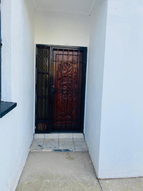 a door with a red gate in a white wall at Phumula Home in Mbabane