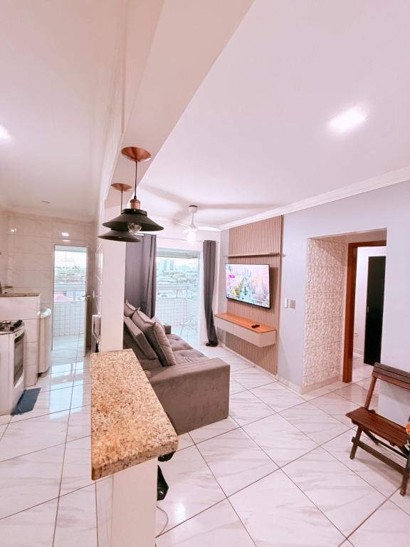 a living room with a couch and a tv at Apartamento Mirim Praia Grande in Praia Grande