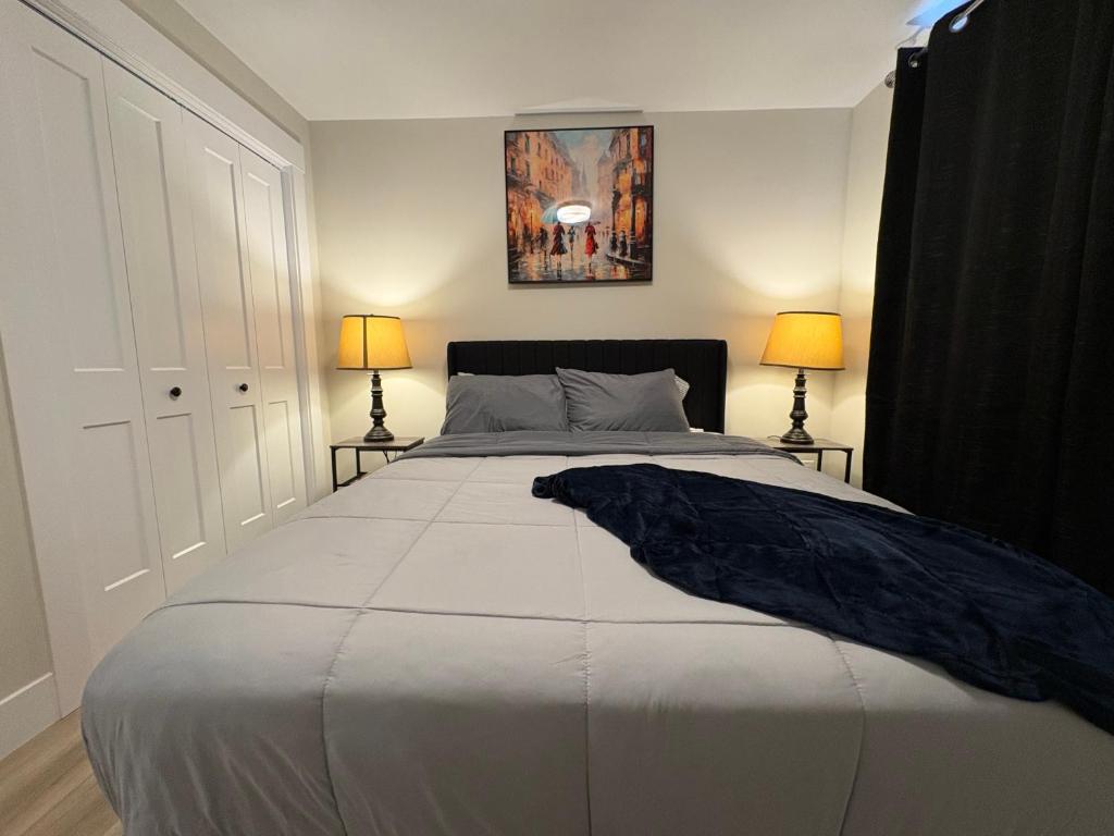 a bedroom with a large white bed with two lamps at Modern Private Suite in Moncton