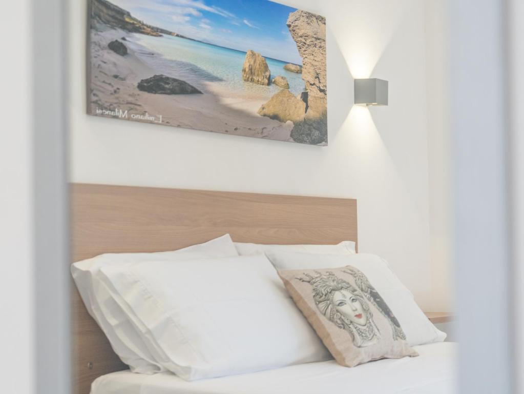 a bed with white pillows and a picture on the wall at Calafato Guest House in Favignana