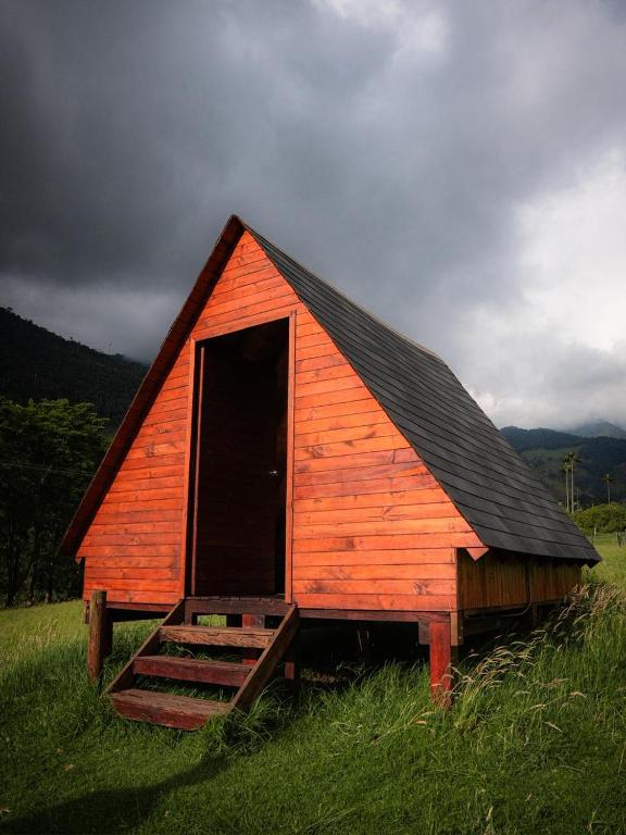 a red barn with a door in a field at Refugio Nidos del Condor Cocora in Salento