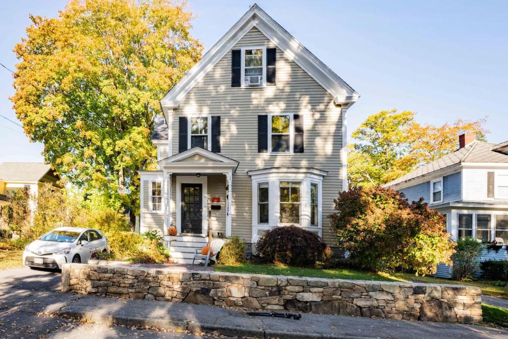 a gray house with a stone wall at Antique Charmer Walk to Downtown KBK in Kennebunk