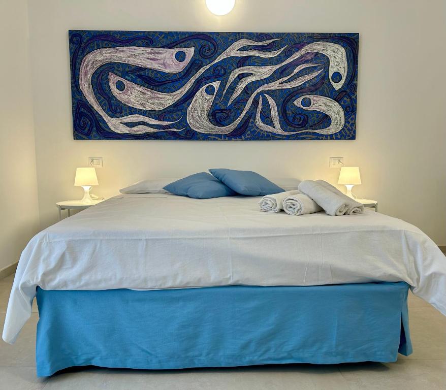 a bedroom with a bed with a painting on the wall at Fortezza Apartments in Le Castella