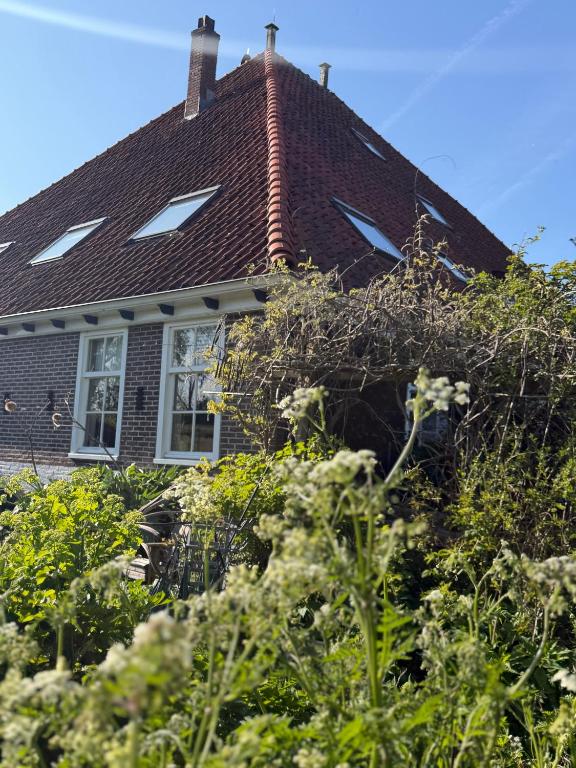 a house with a brown roof and some bushes at B&B De Pauw - Country Home Cooking in Graft