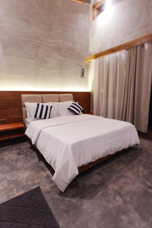 a bedroom with a large bed with white sheets and pillows at Tigbaw in Mactan