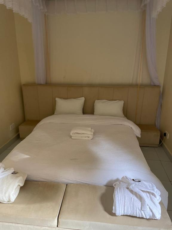 a large white bed with two towels on it at Cleopatra Gardens in Kampala