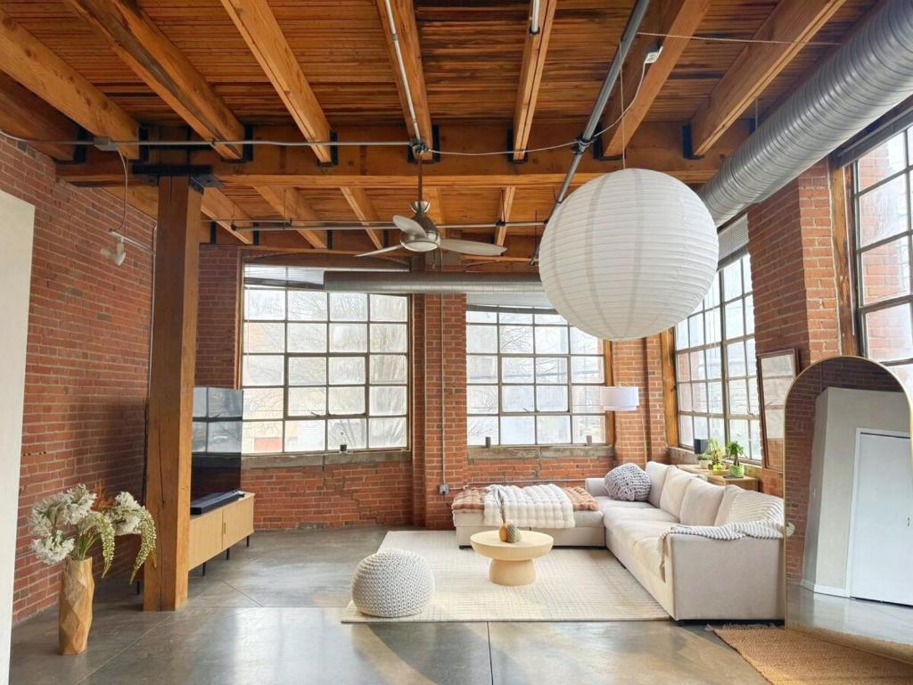 a living room with a brick wall and a large ceiling at Charming Urban Zen in Cleveland