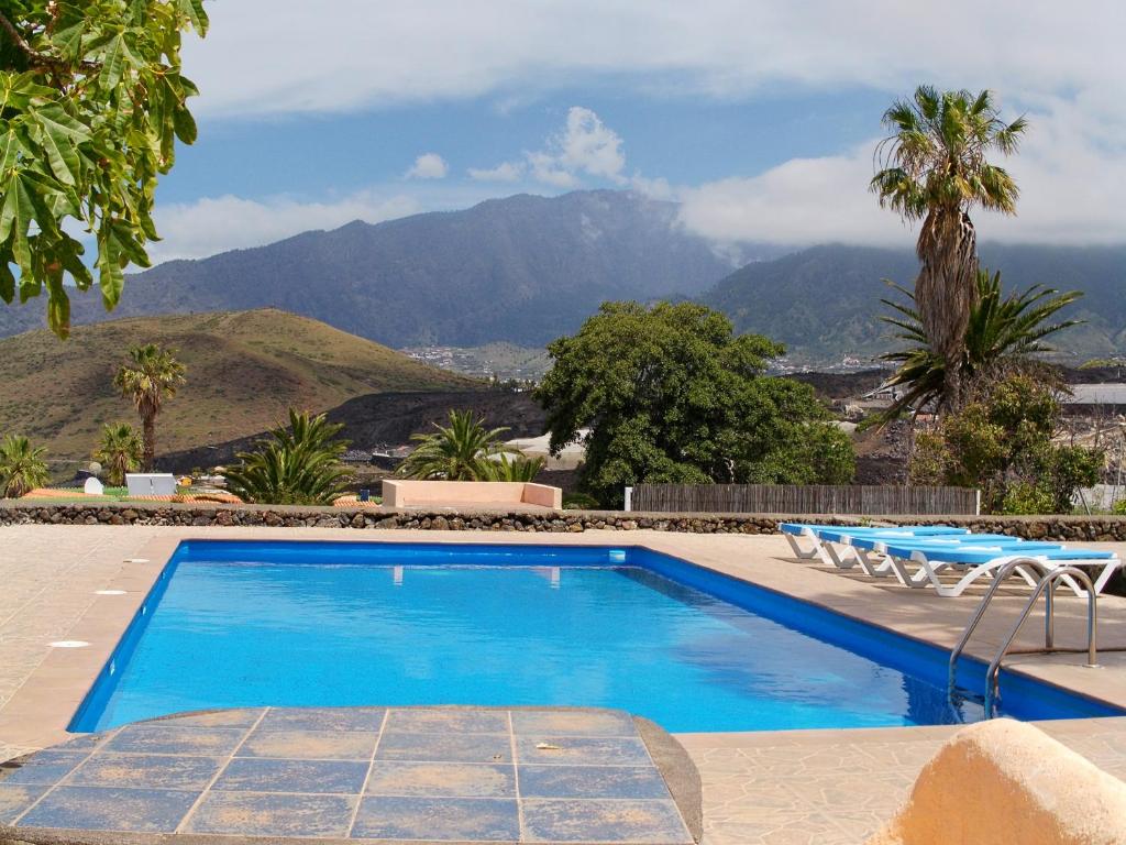 a swimming pool with chairs and mountains in the background at Bungalows El Paradiso in Tazacorte