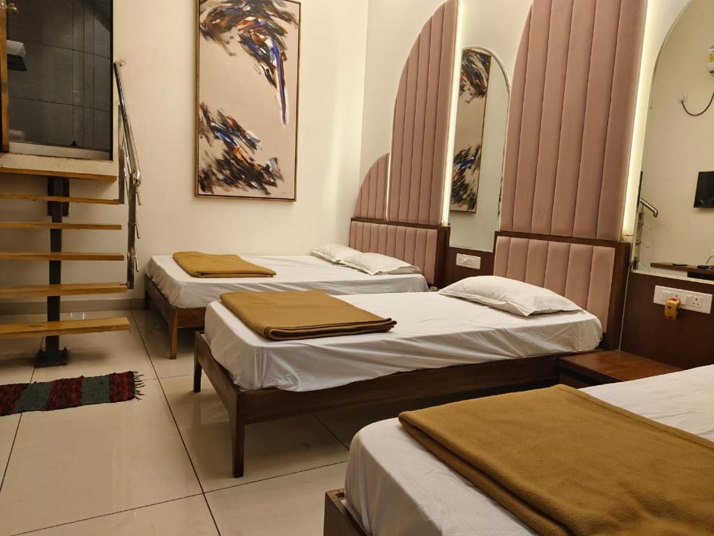 a room with three beds and a staircase at Agatya Homestay in Kolhapur