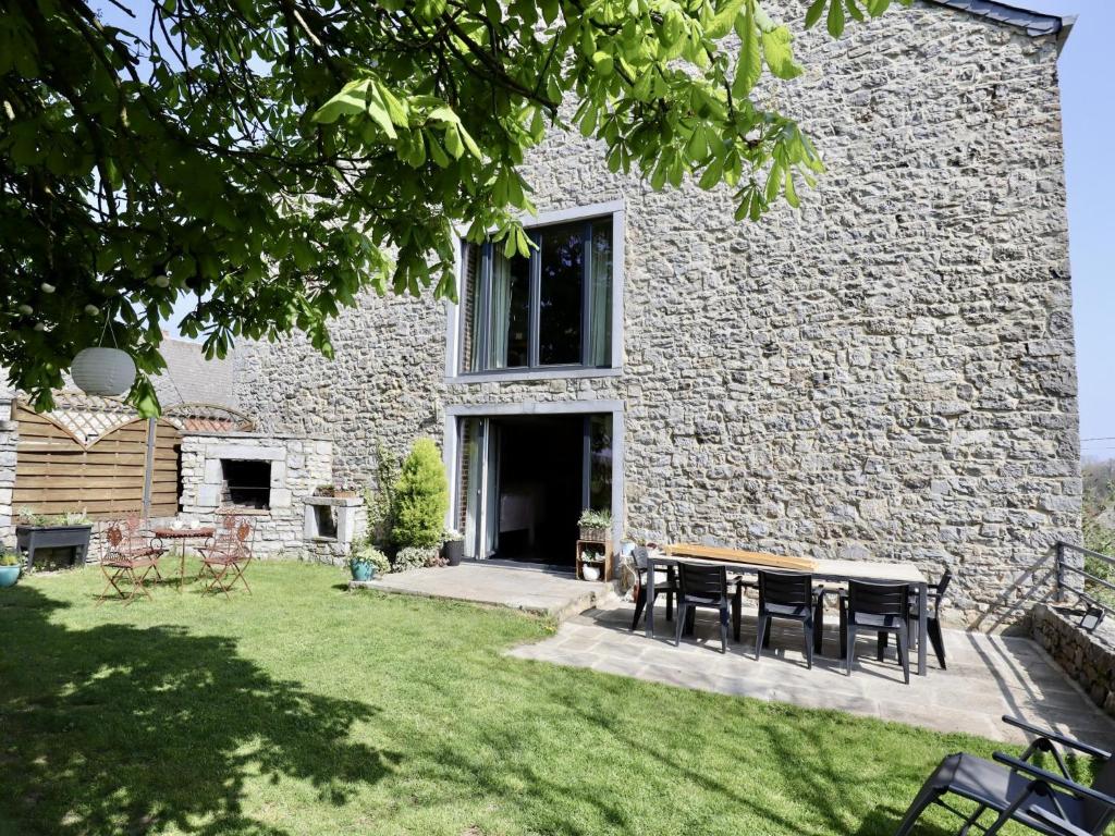 a stone building with tables and chairs in the yard at Le Grenier de Louise in Gimnée
