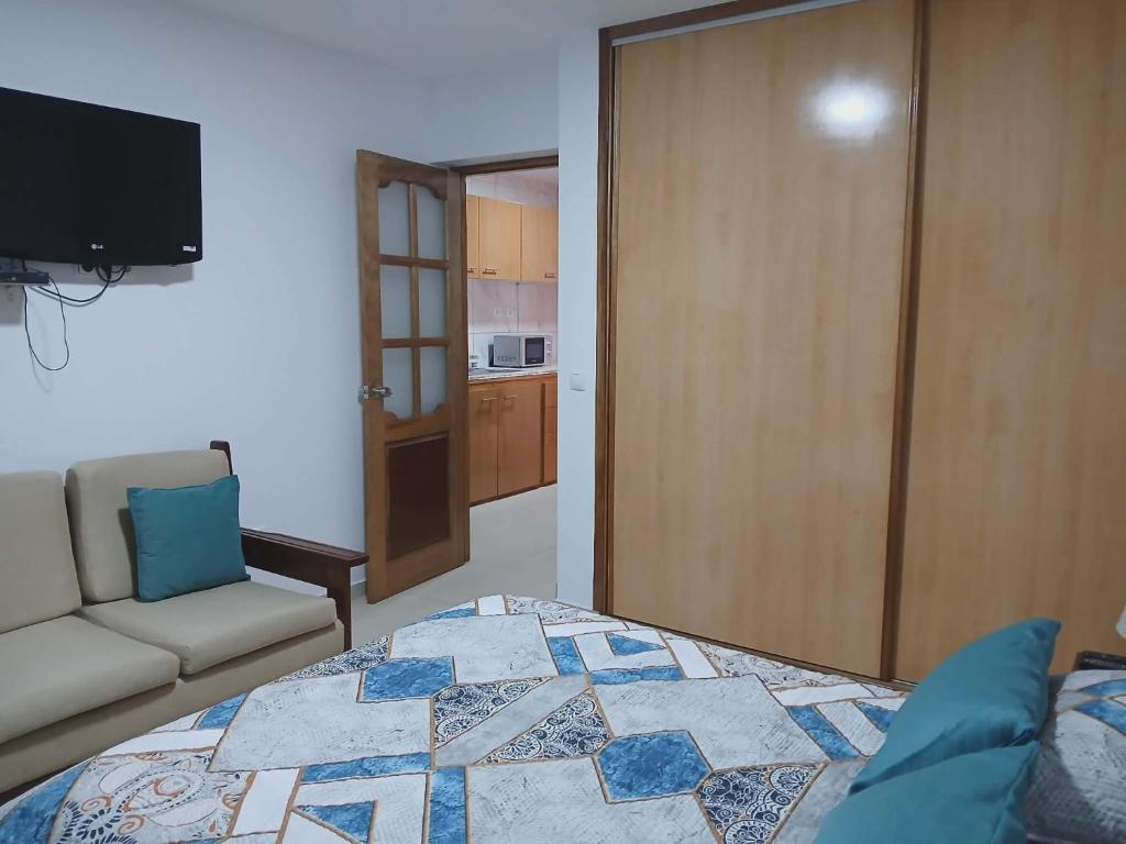a bedroom with a bed and a couch and a television at Vivenda Carlos Daniel in Espargos