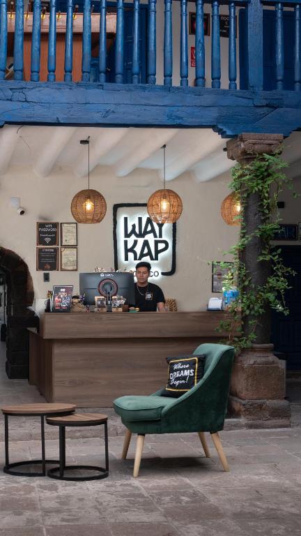 a man sitting at a law bar with a green chair at Way Kap Hostel Cusco in Cusco