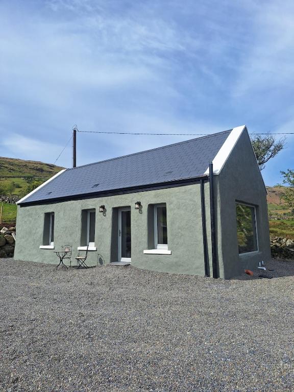 a small house with a black roof at Sunny Hills Cottage in Cornamona