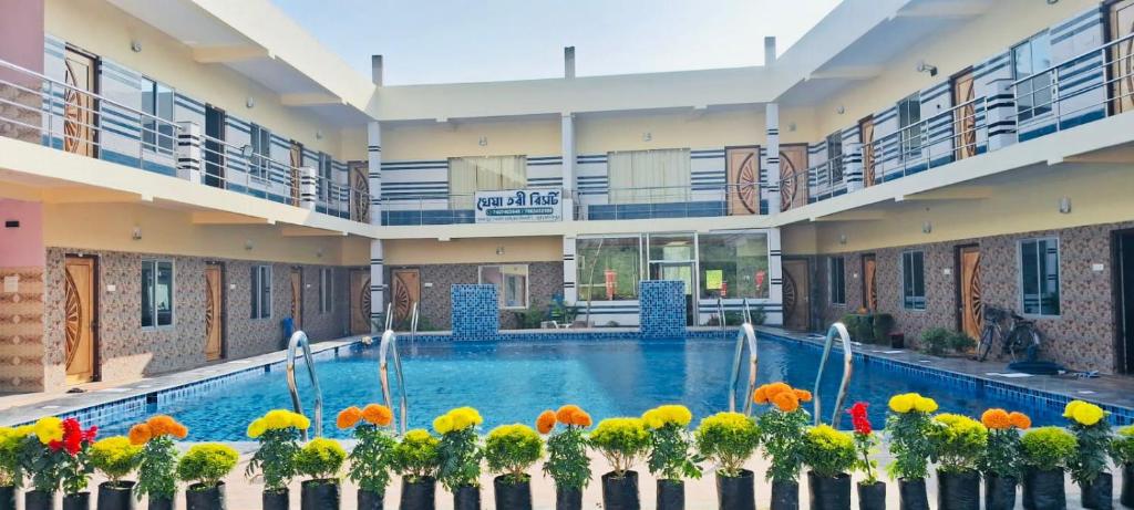 a large building with a swimming pool and flowers at Kheya Tori Resort in Tajpur