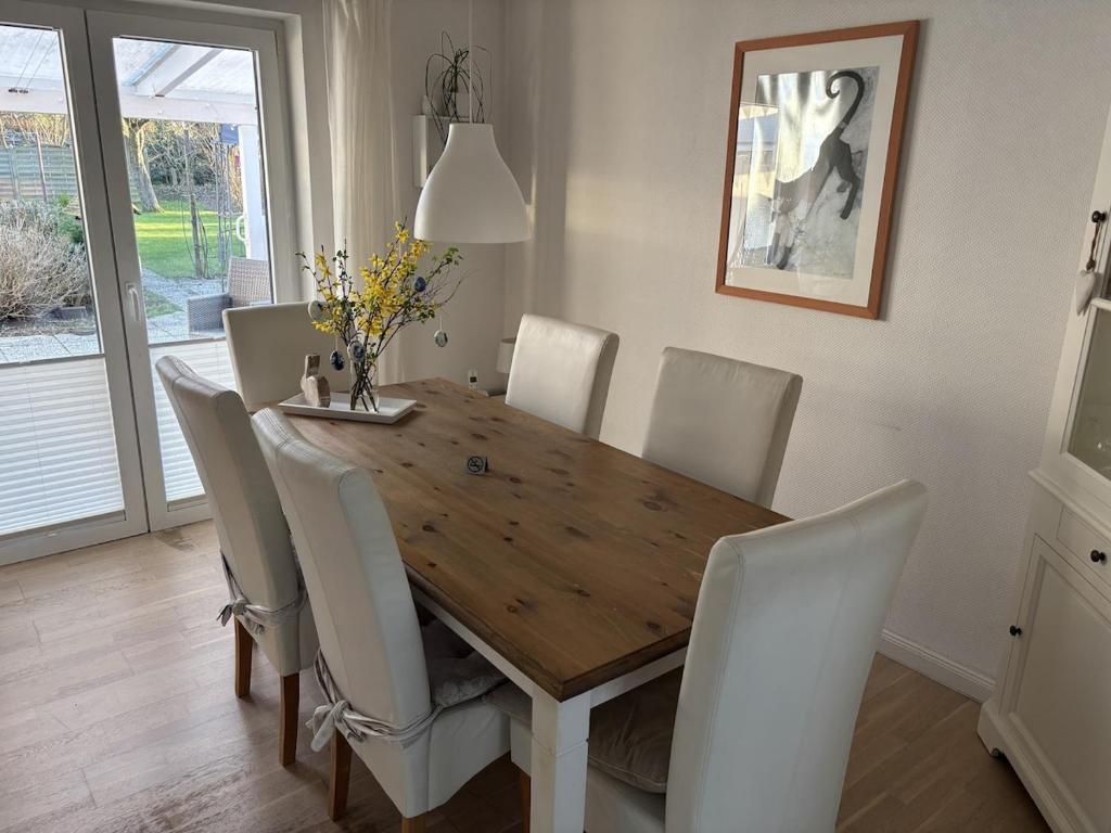 a dining room with a wooden table and white chairs at Ferienhaus Husum Nordsee in Husum