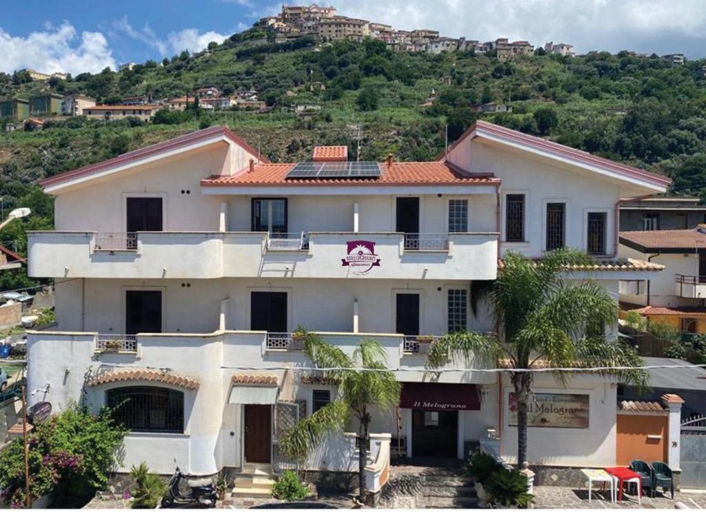 a large white house with a hill in the background at Il Melograno in Nicotera Marina