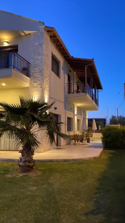 a building with a palm tree in front of it at Kotinos Apartments in Afitos