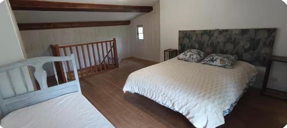a bedroom with a white bed and a staircase at Le cabanon in Valensole