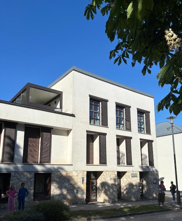 a white building with people standing outside of it at Balaton Vibe Apartman Füred in Balatonfüred