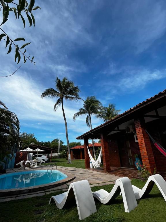 a house with a swimming pool and palm trees at Pousada Brisa do Oceano - Cumbuco in Cumbuco