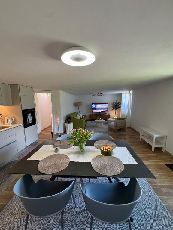 a living room with a table and chairs and a kitchen at Chez Leny in Monthey