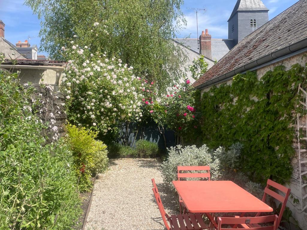 a red table and chairs in a garden with flowers at La Venise de Sologne in Romorantin