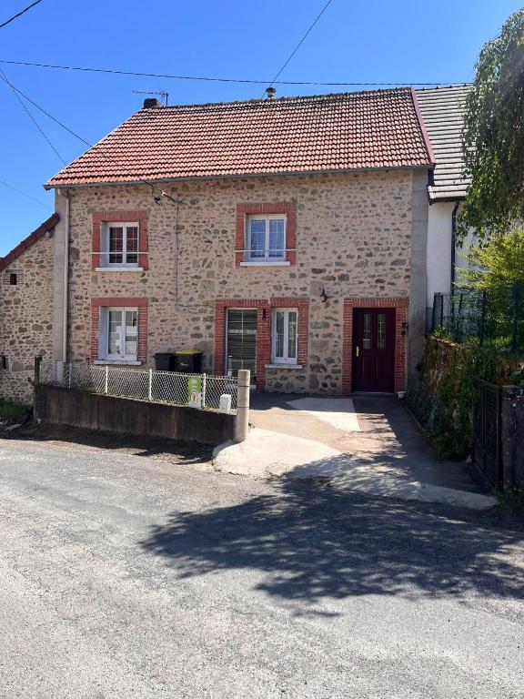 a brick house with a driveway in front of it at Chez Marguerite et Lucienne in Bussière-Dunoise
