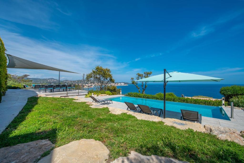 a pool with chairs and umbrellas and the ocean at Ventaou in Sainte-Maxime