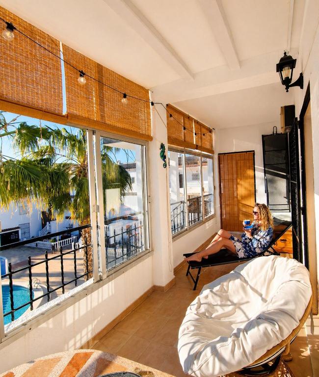 a woman sitting on a couch in a room with windows at Caballito del Mar apartment in Punta Prima