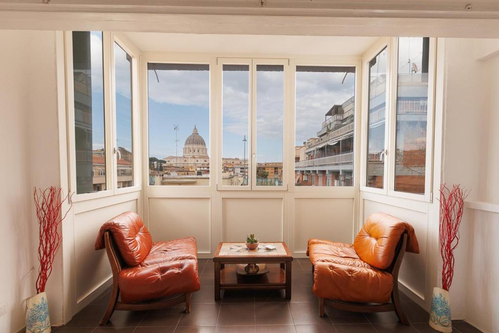 two chairs and a table in a room with windows at St Peter Lodge in Rome