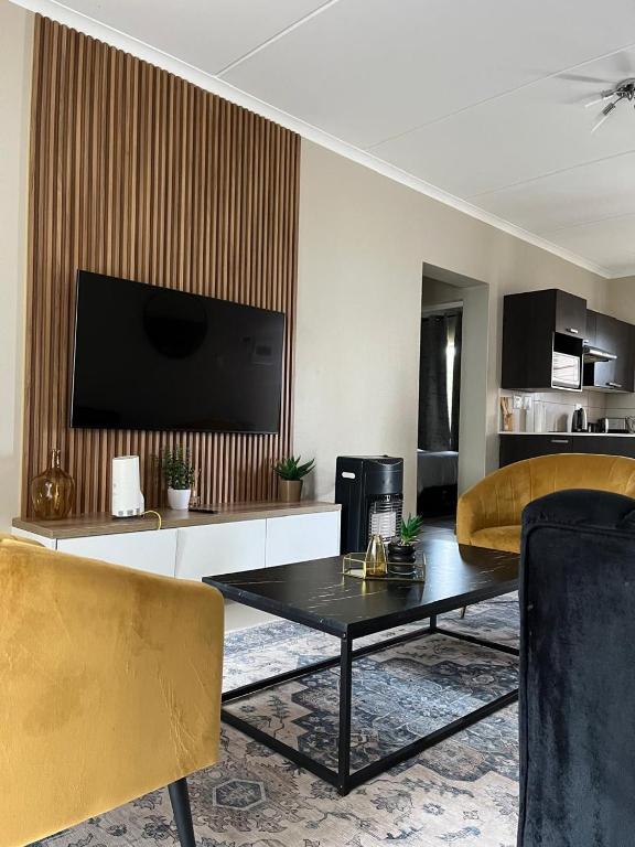 a living room with a television and a table and chairs at Dainfern Luxe Living - 2 Bed in Fourways