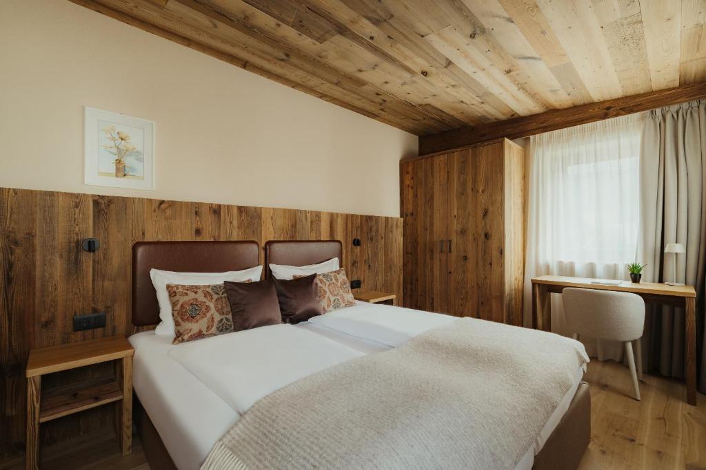 a bedroom with a large bed with wooden walls at Albergo Stella in La Villa