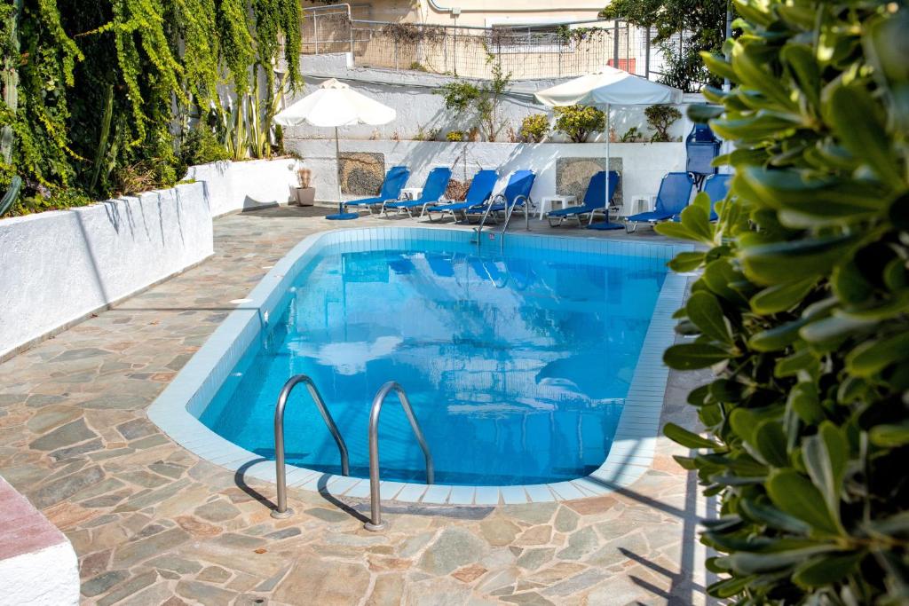a swimming pool with blue chairs next to a building at Blue Cactus village center in Agia Pelagia