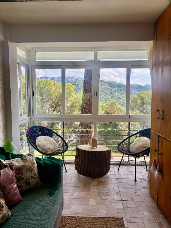 a living room with a large window and a couch at Nibelungos House - Alojamiento artesanal Whimsical frente al Pantano de San Juan - 3 min a pie in San Martín de Valdeiglesias