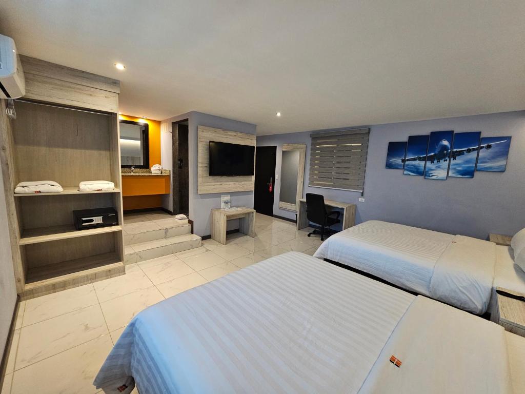 a hotel room with two beds and a television at Hangar Inn TJ - Aeropuerto in Tijuana