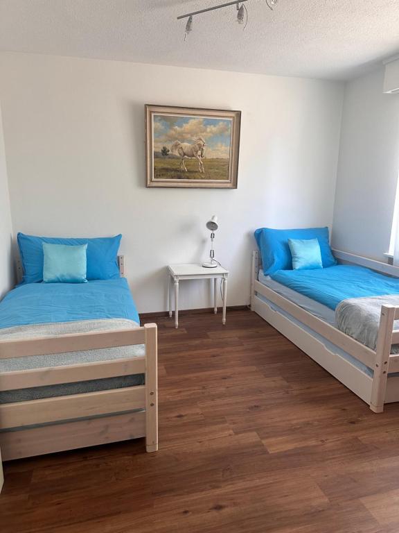 two beds in a room with blue pillows and a table at Appartement 2 chambres avec balcon terrasse in Villars-sur-Glâne