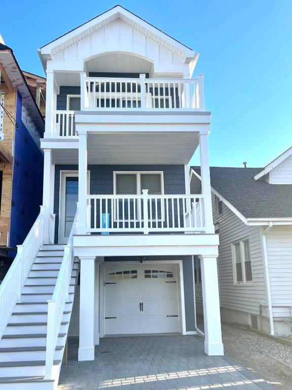 a white house with a balcony and a garage at Cozy Shoregri La! - Beach block! in Seaside Heights