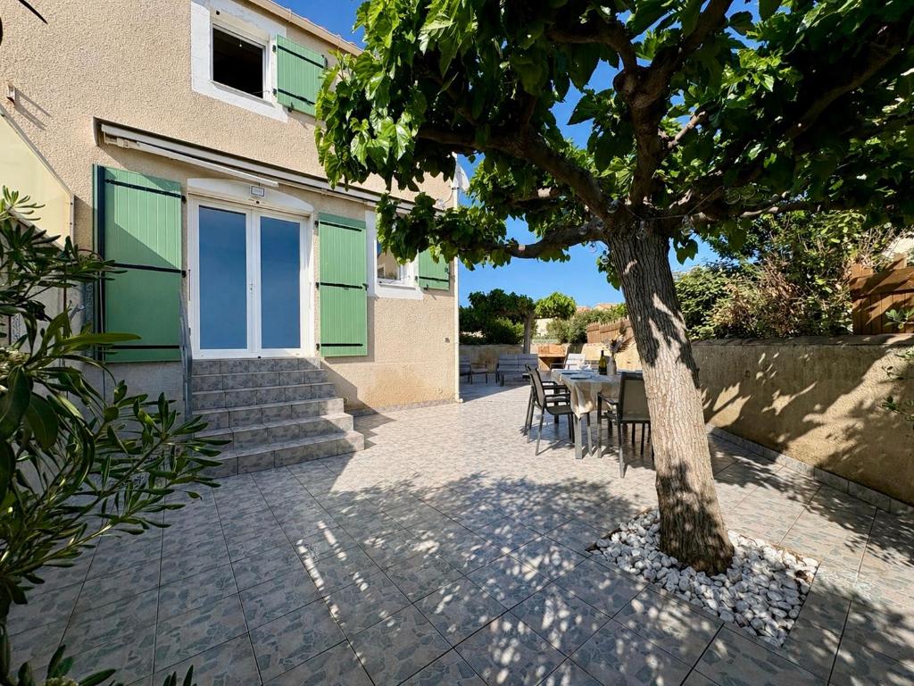 a tree in front of a house with a table at Escales du Sud, Frontignan Plage in Frontignan