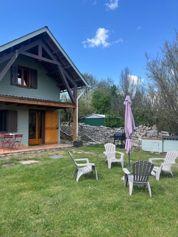 a group of chairs and an umbrella in front of a house at Le chalet de Pierrot in La Malène