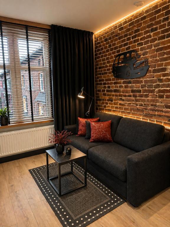 a living room with a couch and a brick wall at Brick Loft Nikiszowiec in Katowice