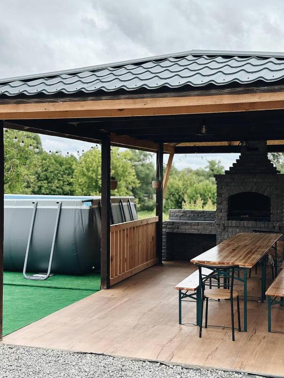 a pavilion with a table and a picnic table on a deck at Зелена долина in Solgutovo