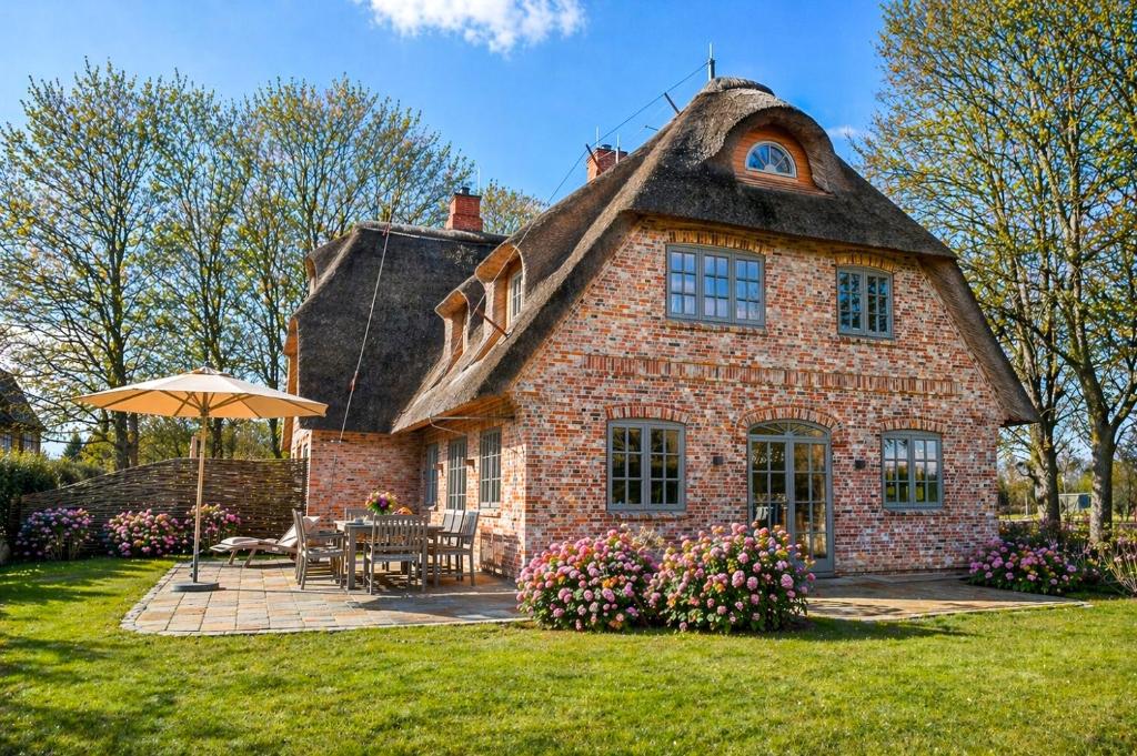 a large brick house with a thatched roof at Haus Lang Libben in Archsum