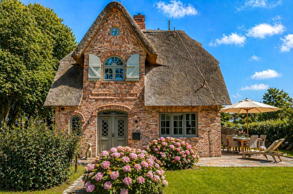 a stone house with a thatched roof at Haus Goed Libben in Archsum
