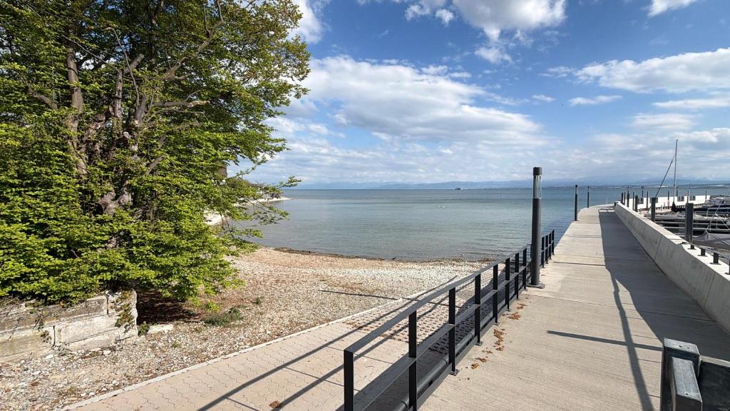 a walkway next to the ocean with a fence at Seegarten Apartment 4 in Hagnau