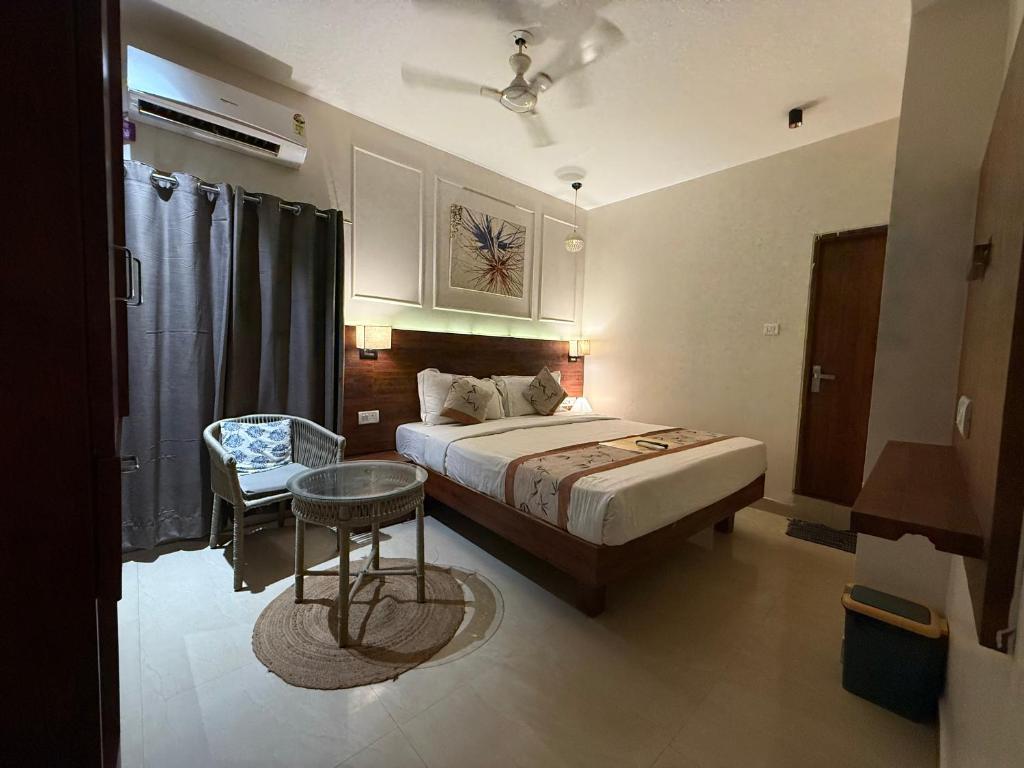 a bedroom with a bed and a table and a chair at RJ14 Accommodations at Baga Beach in Baga