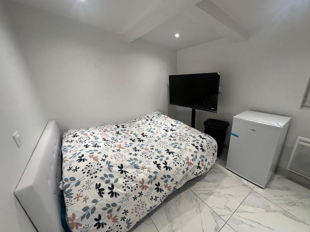 a bedroom with a bed with a flowered comforter and a television at Maison Inviduelle in Aulnay-sous-Bois