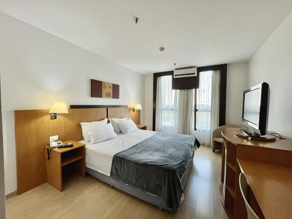 a hotel room with a bed and a flat screen tv at Flat 315 - Comfort Hotel Taguatinga - Particular in Brasília