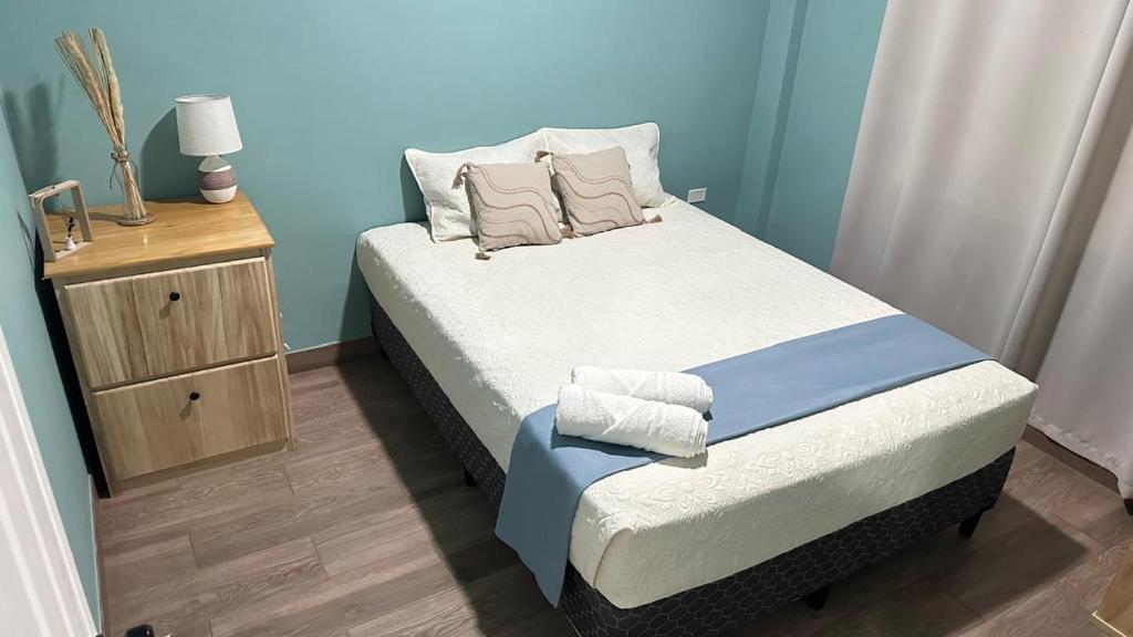 a small bedroom with a bed and a night stand at Churros Apartahotel in La Libertad