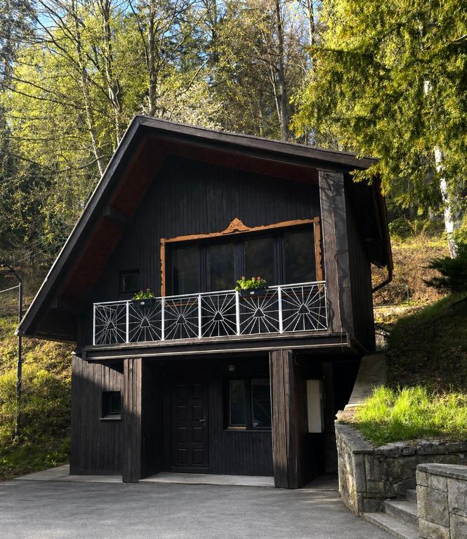 a building with a balcony with flowers on it at Leśny Dworek Marianny 4 osobowy in Miedzygorze